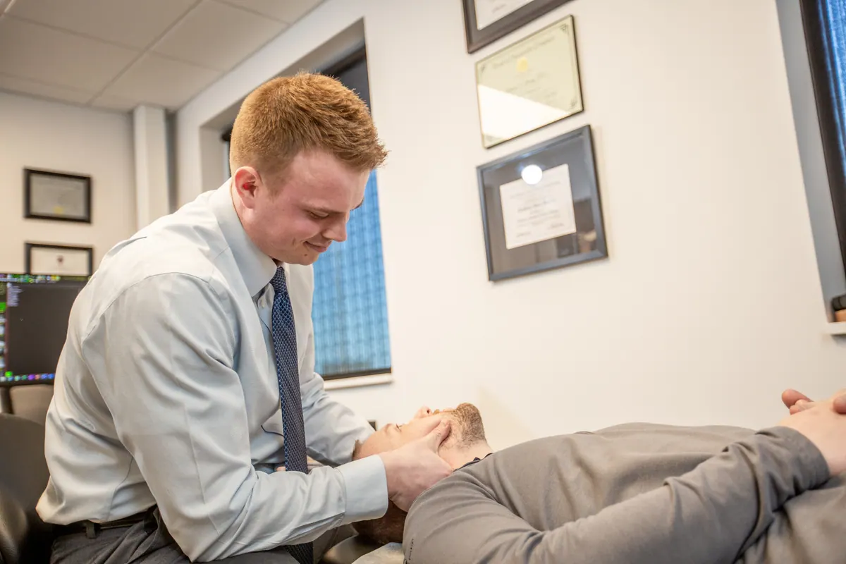 Chiropractor adjusting the neck of a patient lying on a treatment table