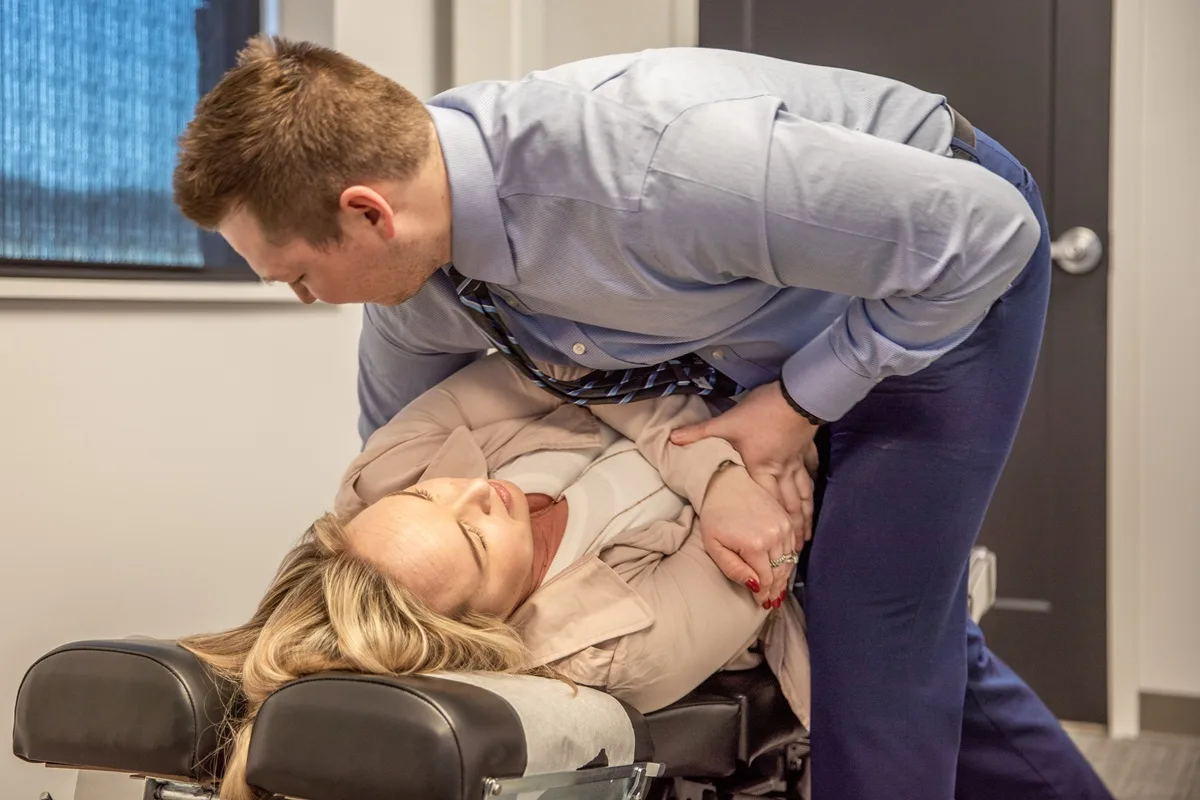 Chiropractor performing a manual spinal adjustment on a patient in a clinical office