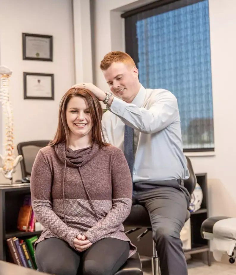 Dr. Andrew Jahner adjusting the neck of a smiling seated patient