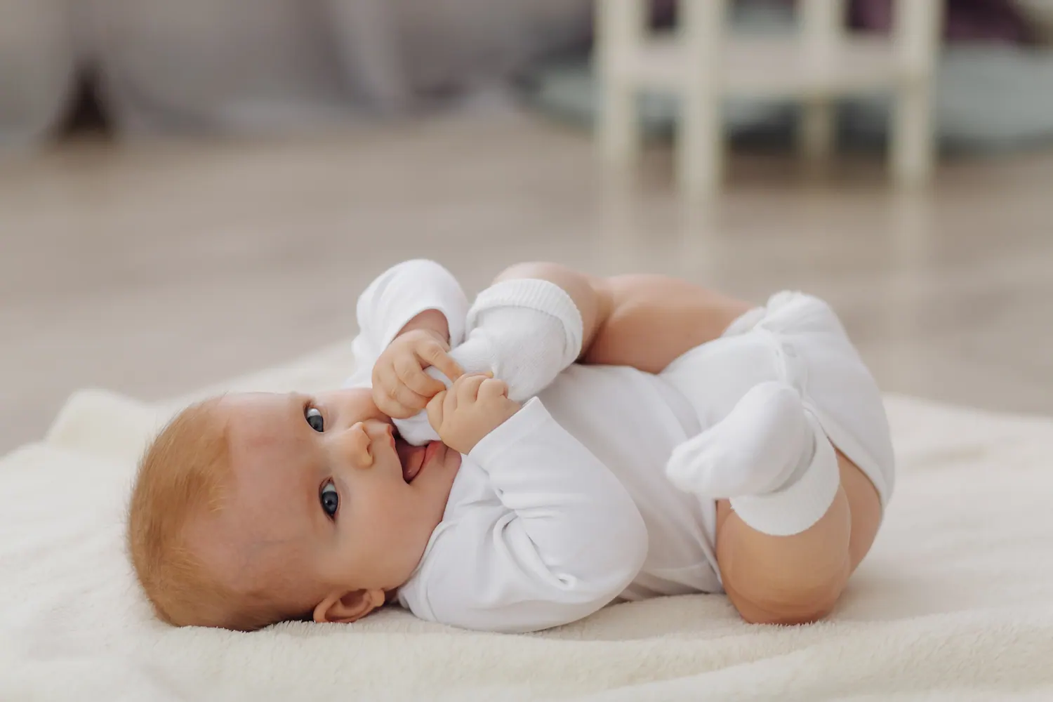 Baby lying on a blanket holding its feet