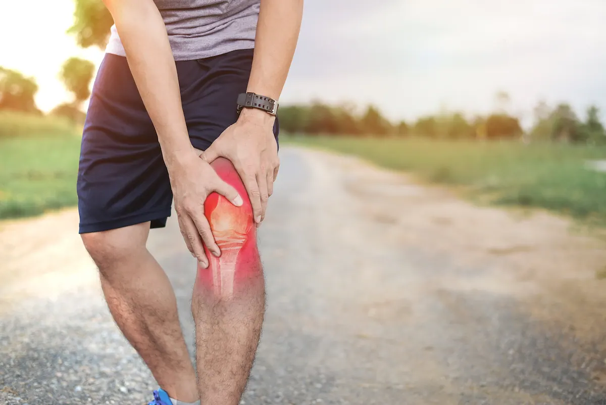 Runner holding his knee with the painful area highlighted in red